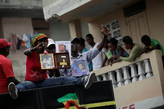 Supporters of Fanmi Lavalas political party show pictures of ex-president Jean Bertrand Aristide and presidential candidate Maryse Narcisse during a demonstration to support interim President Jocelerme Privert in the streets of Port-au-Prince, Haiti, June 21, 2016. (Photo by Andres Martinez Casares/Reuters)