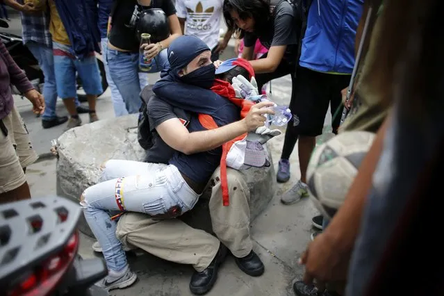 An anti-government demonstrator holds a fellow protester who was injured during clashes with Venezuelan Bolivarian National Guard on the first day of a 48-hour general strike in protest of government plans to rewrite the constitution, in the Bello Campo neighborhood of Caracas, Venezuela, Wednesday, July 26, 2017. (Photo by Ariana Cubillos/AP Photo)