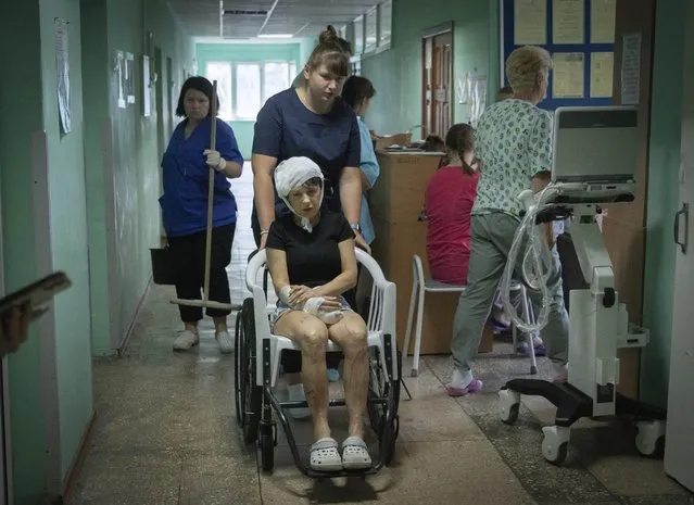 A hospital nurse pushes a wheelchair carrying a woman wounded by the Russian rocket attack at a shopping centre in a city hospital in Kremenchuk in Poltava region, Ukraine, Tuesday, June 28, 2022. (Photo by Efrem Lukatsky/AP Photo)