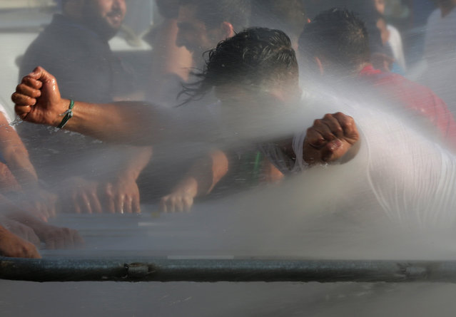 Lebanese activists are sprayed with water as they try to cross to the government house, during a protest against the ongoing trash crisis, in downtown Beirut, Lebanon, Wednesday, Aug. 19, 2015. Lebanon's health minister says the country is on the brink of a "major health disaster" unless an immediate solution is found for its mounting trash problem. (Photo by Hussein Malla/AP Photo)