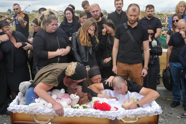 Relatives and friends attend the funeral ceremony for Liza, 4-year-old girl killed by Russian attack, in Vinnytsia, Ukraine, Sunday, July 17, 2022. Wearing a blue denim jacket with flowers, Liza was among 23 people killed, including two boys aged 7 and 8, in Thursday's missile strike in Vinnytsia. Her mother, Iryna Dmytrieva, was among the scores injured. (Photo by Efrem Lukatsky/AP Photo)