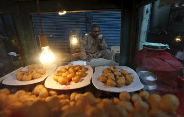 Shaukat Ali, drinks a bowl of tea, while waiting for customers to sell “gol gapyy”, a traditional street food, along a market in Karachi, Pakistan, August 19, 2015. Shaukat sells a plate of gol gapyy Pakistani Rupees 50 ($0.49) and earns around 1500 ($14.7) per day. (Photo by Akhtar Soomro/Reuters)