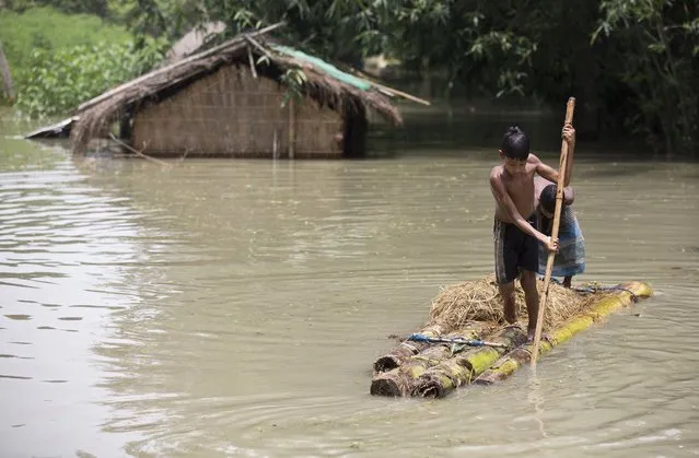Flood affected boys move on a banana raft near partially submerged houses in Morigaon district east of Gauhati, Assam, India, Tuesday, August 15, 2017. Heavy monsoon rains have unleashed landslides and floods that killed dozens of people in recent days and displaced millions more across northern India, southern Nepal and Bangladesh. (Photo by Anupam Nath/AP Photo)