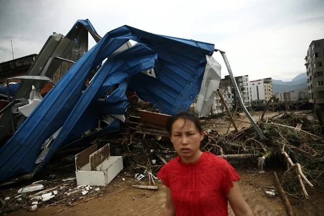 This photo taken on July 10, 2016 shows a woman walking past debris in the aftermath of a tropical storm in Bandong town, in Minqing county, east China's Fujian province. (Photo by AFP Photo/Stringer)