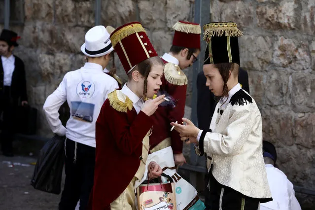 Ultra-Orthodox Jewish children smoke as they are dressed-up in costumes during celebrations marking the Jewish holiday of Purim in Jerusalem's Mea Shearim neighbourhood on March 11, 2020. (Photo by Ammar Awad/Reuters)