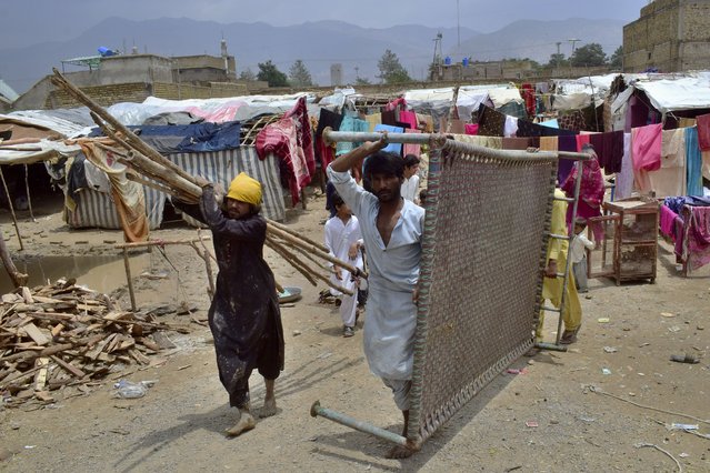People carry a cot and other items after salvaging them from their houses that were damaged by heavy rain, on the outskirts of Quetta, Pakistan, Tuesday, July 5, 2022. At least six people, including women and children, were killed when the roofs of their homes collapsed in heavy rains lashing southwestern Pakistan and other parts of the country, a provincial disaster management agency said. (Photo by Arshad Butt/AP Photo)