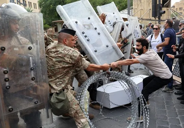 Lebanese activists confront soldiers guarding the entrance of the country's parliament building during a demonstration in the centre of the capital Beirut, on August 4, 2022, on the day that crisis-hit Lebanon marks two years since a giant explosion ripped through the capital. On August 4, 2020, the dockside blast of haphazardly stored ammonium nitrate, one of history's biggest non-nuclear explosions, killed more than 200 people, wounded thousands and decimated vast areas of the capital. (Photo by Anwar Amro/AFP Photo)