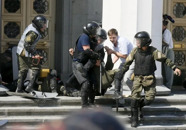 Ukrainian servicemen carry an injured comrade away from the parliament building in Kiev, Ukraine, August 31, 2015. (Photo by Valentyn Ogirenko/Reuters)
