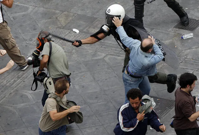 Riot policeman uses his baton against news photographer Panagiotis Tzamaros, who is on assignment for AFP, during a demonstration in Athens' Syntagma (Constitution) square October 5, 2011. Tzamaros suffered light head wounds and bruises. (Photo by Yannis Behrakis/Reuters)