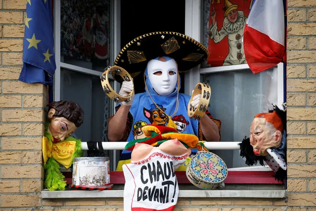 A person wearing protective gloves and carnival mask plays instruments from a window during the parade of “Carnaval de Cassel” as a lockdown is imposed to slow the spread of the coronavirus disease (COVID-19) in Cassel, France on April 13, 2020. (Photo by Pascal Rossignol/Reuters)