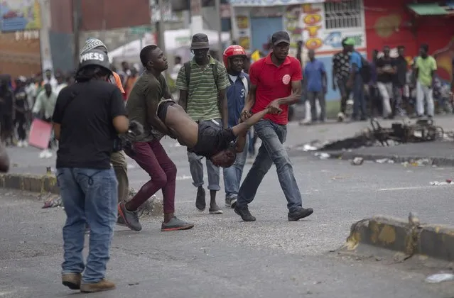 Men carry the body of a man after he was shot in the head by unknown assailants during a protest in Port-au-Prince, Haiti, Monday, August 22, 2022. (Photo by Odelyn Joseph/AP Photo)