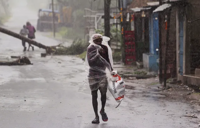A man covers himself with a plastic sheet and walks in the rain ahead of Cyclone Amphan landfall, at Bhadrak district, in the eastern Indian state of Orissa, Wednesday, May 20, 2020. A strong cyclone blew heavy rains and strong winds into coastal India and Bangladesh on Wednesday after more than 2.6 million people were moved to shelters in a frantic evacuation made more challenging by coronavirus. (Photo by AP Photo/Stringer)