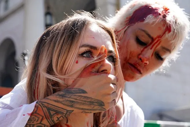 Samy Rose Moshiri, an Iranian American artist and activist, covers the mouth of Belarusian activist Yadviga Krasovskaya after dousing themselves in fake blood on stage at a Freedom Rally for Iran, in support of Iranian women and against the death of Mahsa (Zhina) Amini, outside City Hall in Los Angeles, California, U.S., October 1, 2022. (Photo by Bing Guan/Reuters)