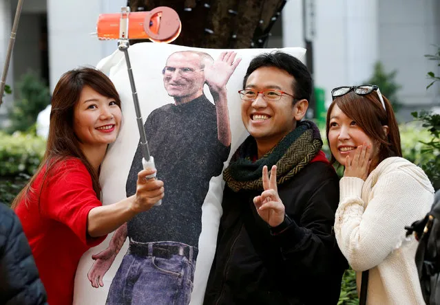 Ayano Tominaga (L) and other customers pose for a selfie photo with a cushion printed with a portrait of Apple co-founder Steve Jobs on it, as they wait in queue for the release of Apple's new iPhone X in front of the Apple Store in Tokyo's Omotesando shopping district, Japan, November 3, 2017. (Photo by Toru Hanai/Reuters)