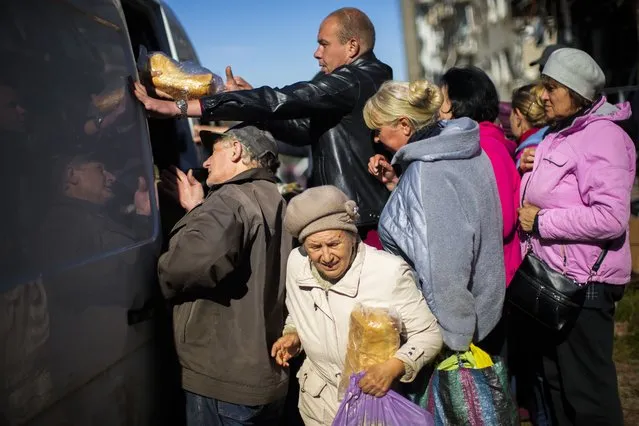 Locals receive food and everyday necessities given by Ukrainian volunteers in Izium, Ukraine, Wednesday, October 12, 2022. Residents in Izium have been living with no gas, electricity or running water supply since the beginning of September. (Photo by Francisco Seco/AP Photo)