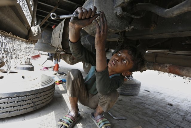 Sami Ullah, 10 years old, works at an automotive repair shop to earn living for his family in Lahore, Pakistan, Saturday, June 12, 2021. The International Labor Organization (ILO) observes June 12 as the World Day Against Child Labor to highlight the plight of child laborers. (Photo by K.M. Chaudary/AP Photo)