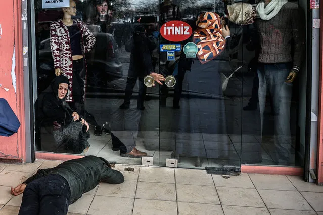 A man lies on the pavement after Turkish anti-riot police officers fired tear gas to disperse supporters in front of the headquarters of the Turkish daily newspaper Zaman in Istanbul on March 5, 2016, after Turkish authorities seized the headquarters in a midnight raid. Turkish authorities were on March 5 in control of the newspaper staunchly opposed to President Recep Tayyip Erdogan after using tear gas and water cannon to seize its headquarters in a dramatic raid that raised fresh alarm over declining media freedoms. Police fired the tear gas and water cannon just before midnight at a hundreds-strong crowd that had formed outside the headquarters of the Zaman daily in Istanbul following a court order issued earlier in the day. (Photo by Ozan Kose/AFP Photo)
