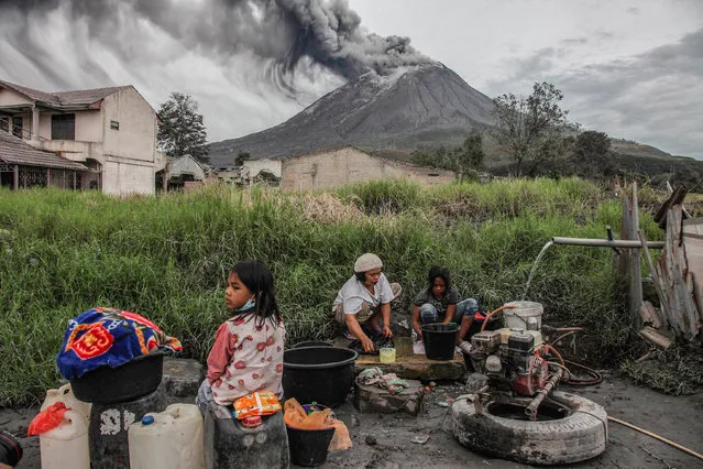 Villagers do their laundry as Mount Sinabung spews volcanic materials during an eruption, in Karo, North Sumatra, Indonesia  on August 14, 2020. Sinabung is among more than 120 active volcanoes in Indonesia, which is prone to seismic upheaval due to its location on the Pacific “Ring of Fire”, an arc of volcanoes and fault lines encircling the Pacific Basin. (Photo by AP Photo/Rex Features/Shutterstock)