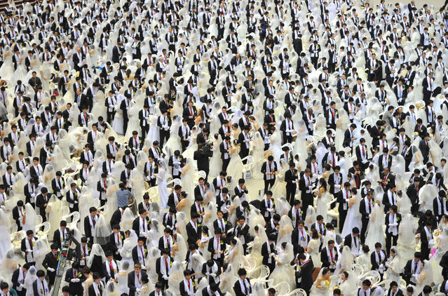 Rows of newly-wedded brides and grooms stand and mingle at the Unification Church's mass wedding held at its headquarters in Gapyeong, east of Seoul, on February 17, 2013, that saw some 3,500 couples matched by the church tie the knot.  The Unification Church, set up by Sun Myung Moon in Seoul in 1954, is one of the world's most controversial religious organisations, and its devotees are often dubbed “Moonies” after the founder. (Photo by Kim Jae-Hwan/AFP Photo)