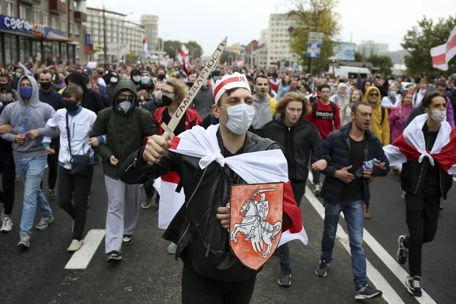 Demonstrators, one of them wearing an old Belarusian nation flag and holding a cardboard sword reading “solidarity” march during an opposition rally to protest the official presidential election results in Minsk, Belarus, Sunday, September 27, 2020. (Photo by TUT.by via AP Photo)