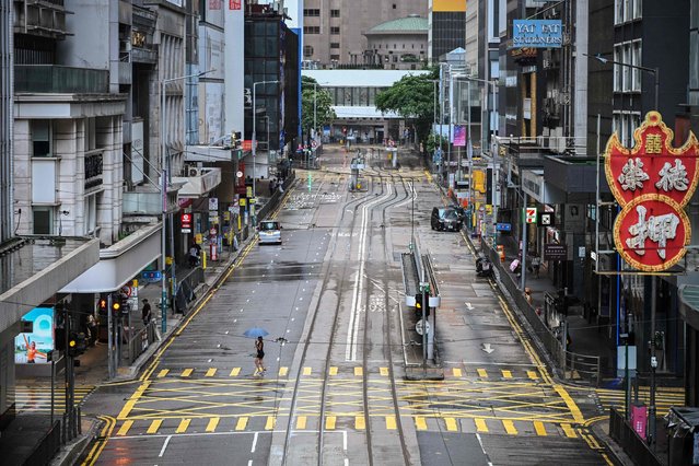 A woman crosses an empty street in the Central district as Typhoon Wipha moves towards Hong Kong on July 20, 2025. (Photo by Peter Parks/AFP Photo)