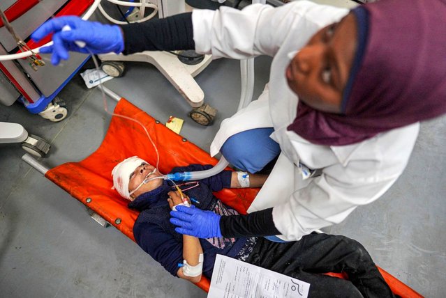 A medic gives first aid to an injured child laying on a stretcher at Al-Aqsa Martyrs Hospital in Deir el-Balah, central Gaza, on April 16, 2024, amid ongoing battles between Israel and the Palestinian militant group Hamas. (Photo by AFP Photo/Stringer)