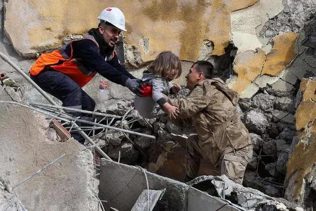 Muhammet Ruzgar, 5, is carried out by rescuers from the site of a damaged building, following an earthquake in Hatay, Turkey on February 7, 2023. (Photo by Umit Bektas/Reuters)