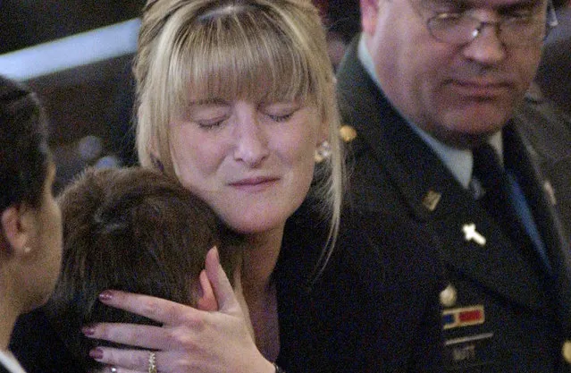 Six-year-old Tyler Jordan is hugged by his mother Amanda while U.S. Army Chaplain Captain David Nott looks on during the funeral of the boy's father, United States Marine Gunnery Sgt. Philip Jordan, at Holy Family Church in Enfield, Connecticut, on April 2, 2003. Sgt. Jordan was killed during fighting outside Nasiriyah on March 23 in the early days of the U.S. led invasion of Iraq. (Photo by Chip East/Reuters/The Atlantic)
