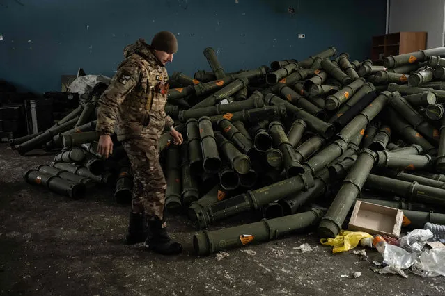 A Ukrainian serviceman of the 93rd brigade stands near a pile of empty mortar shell containers in Bakhmut on February 15, 2023, amid the Russian invasion of Ukraine. (Photo by Yasuyoshi Chiba/AFP Photo)