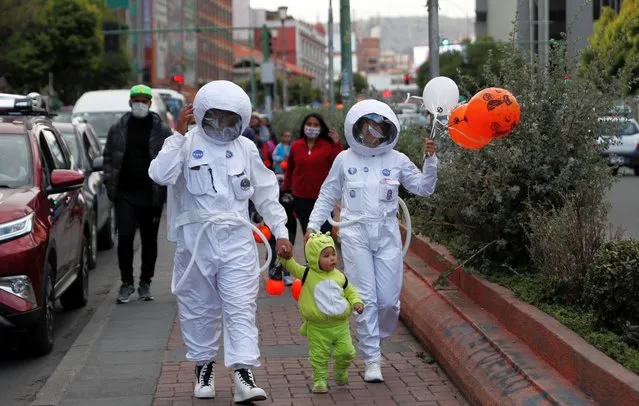 People wearing NASA astronaut costumes trick-or-treat with a child dressed as an alien on Halloween in La Paz, Bolivia, Saturday, October 31, 2020, amid the COVID-19 pandemic. (Photo by Juan Karita/AP Photo)