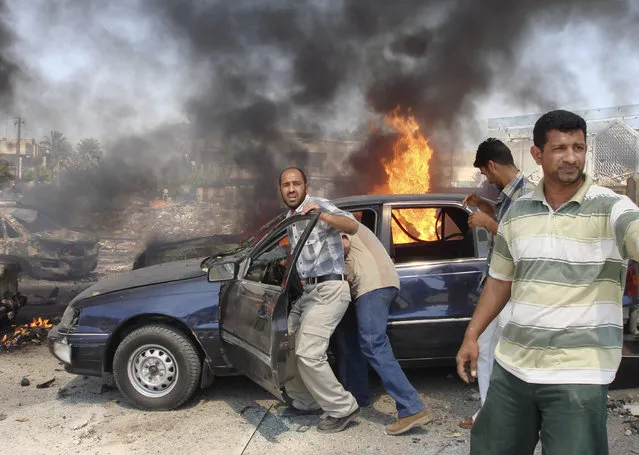 Men try to push a vehicle away from the scene of a suicide bomb attack in Baghdad, April 5, 2007. (Photo by Reuters/Stringer)