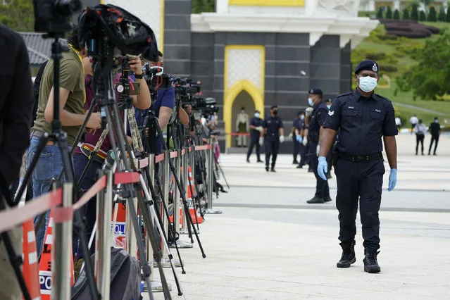 Police wearing a face mask to help curb the spread of the coronavirus guard media outside National Palace in Kuala Lumpur, Malaysia, Sunday, October 25, 2020. Malay rulers hold a special meeting on Sunday to discuss the government's plan to declare an emergency to tackle the worsening COVID-19 situation. (Photo by Vincent Thian/AP Photo)