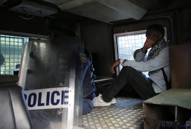 A student demanding free education is seen in a police armoured vehicle after being detained during protests outside the University of the Witwatersrand at Braamfontein, in Johannesburg, South Africa, October 10, 2016. (Photo by Siphiwe Sibeko/Reuters)