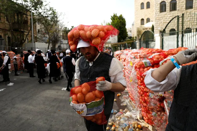 An Ultra-Orthodox Jewish man carries sacks of potatoes at a food distribution center providing food products for families ahead of the upcoming Jewish holiday of Passover near Jerusalem's Mea Shearim neighbourhood, March 27, 2018. (Photo by Ronen Zvulun/Reuters)