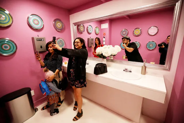 Visitors take a bathroom selfie, in a two-sided room that lacks self-reflection during a VIP media preview ahead of the opening of The Museum of Selfies in Glendale, California, U.S., March 29, 2018. (Photo by Mario Anzuoni/Reuters)