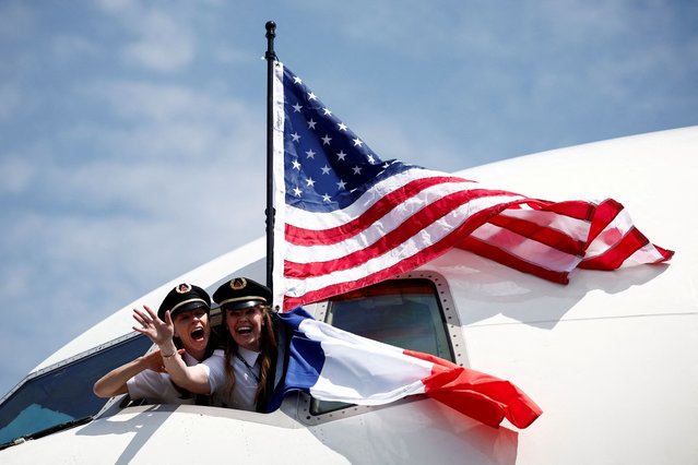 Women wearing Delta Airlines pilot hats wave from the cockpit window with French and US flags at the Deauville-Normandie Airport, in Deauville, Normandy region, France, on June 3, 2024. (Photo by Benoit Tessier/Reuters)