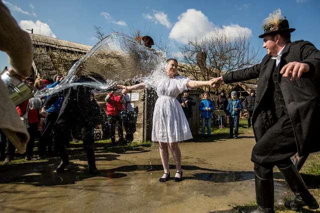 Members of the Mayossa folk dance group pour water on a young woman in Kiskunmajsa, Hungary on April 2, 2018. According to an old Hungarian tradition, celebrated for several hundred years, young men pour water on young women, who in exchange present their sprinklers with beautifully colored eggs on Easter Monday. (Photo by Mudra László/Origo Photo)