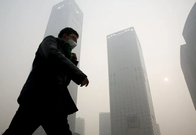A man wearing a mask makes his way at a financial district during a heavily polluted day in Beijing, China November 30, 2015. (Photo by Kim Kyung-Hoon/Reuters)