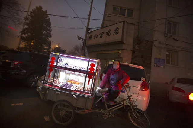 A woman selling snacks waits with her bicycle cart outside of a subway station amid heavy pollution and fog in Beijing, Tuesday, December 1, 2015. Schools in the Chinese capital kept students indoors and parents brought their kids to hospitals with breathing ailments today as Beijing grapples with extremely severe air pollution for the fifth straight day. (Photo by Mark Schiefelbein/AP Photo)