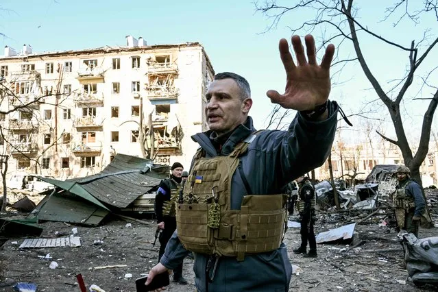 Kyiv's mayor Vitali Klitschko holds people away from a five-storey residential building that partially collapsed after a shelling in Kyiv on March 18, 2022, as Russian troops try to encircle the Ukrainian capital as part of their slow-moving offensive. Authorities in Kyiv said one person was killed early today when a downed Russian rocket struck a residential building in the capital's northern suburbs. They said a school and playground were also hit. (Photo by Sergei Supinsky/AFP Photo)