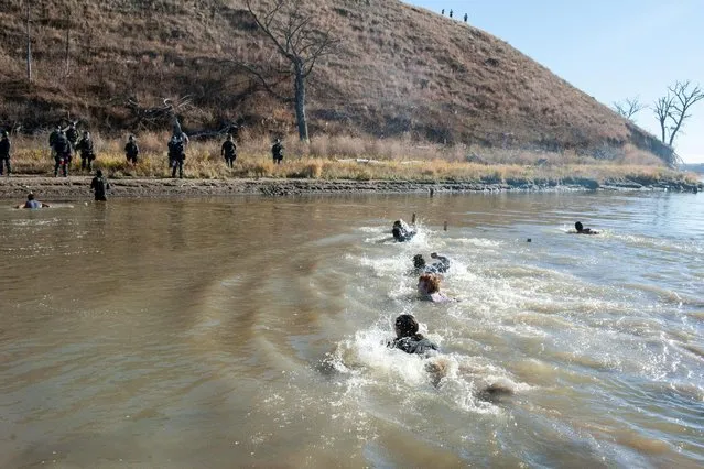 People swim across a river to where the police officers are standing guard during a protest against the building of a pipeline near the Standing Rock Indian Reservation near Cannonball, North Dakota, U.S. November 2, 2016. (Photo by Stephanie Keith/Reuters)