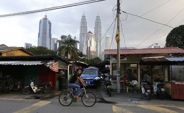 A cyclist passes a carwash in Kampung Baru, the last remaining traditional Malay settlement in Kuala Lumpur, January 18, 2015. The Malaysian government announced plans for a $12 billion redevelopment of the 100-year-old settlement located in the heart of the Kuala Lumpur, local media reported. (Photo by Olivia Harris/Reuters)