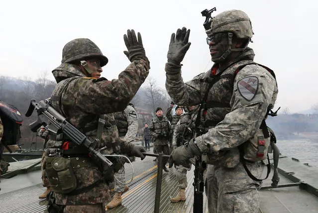 Soldiers from South Korea (L) and the US (R) gesture as they set up a floating bridge during a US-South Korea joint river crossing exercise in the border county of Yeoncheon, northeast of Seoul, on December 10, 2015. The Korean peninsula is the world's last Cold War frontier as Stalinst North Korea and pro-Western South Korea have been technically at war since the 1950-53 Korean War. (Photo by AFP Photo/Yonhap)