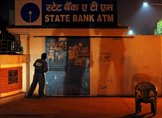 A security guard closes the gate of a State Bank ATM in the northern city of Kanpur, India November 9, 2016. (Photo by Adnan Abidi/Reuters)