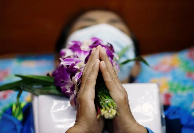 A devotee lies down and prays inside a coffin to trick death and improve luck at a temple in Bangkok, Thailand on January 27, 2021. (Photo by Soe Zeya Tun/Reuters)