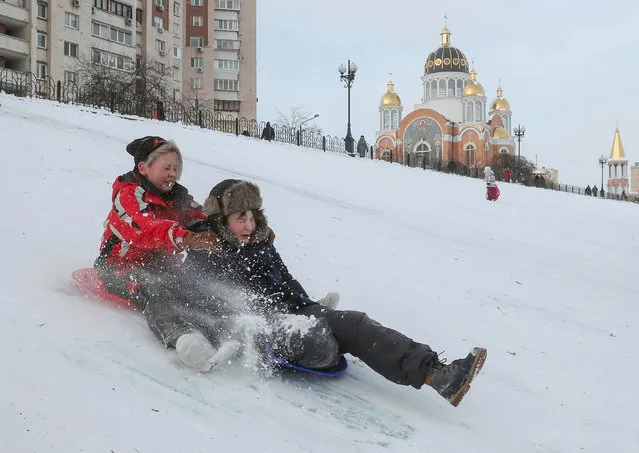 Ukrainian children fool around on a snow-covered hill in Kiev, Ukraine, 18 January 2021. A strong frost with temperatures up to minus 20 degrees Celsius has continued in Ukraine for several last days. (Photo by Sergey Dolzhenko/EPA/EFE)