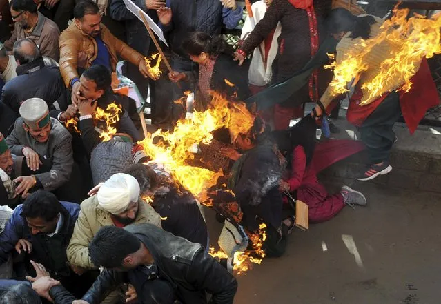 Activists from India's main opposition Congress party try to flee after their clothes caught fire while they were trying to burn an effigy of Indian Prime Minister Narendra Modi during a protest in Shimla, India, December 14, 2015. Local media reported Sukhwinder Singh Sukhu, chief of Himachal Pradesh Congress Committee, saying that at least five Congress activists suffered burns on Monday during the protest against the central government, accusing it of a “vendetta” against the Gandhi family by launching court cases against them. (Photo by Reuters/Stringer)