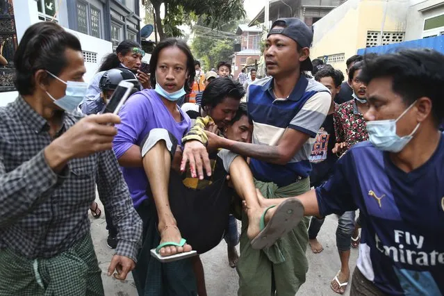 A man is carried after police dispersed protesters in Mandalay, Myanmar on Saturday, February 20, 2021. Security forces in Myanmar ratcheted up their pressure against anti-coup protesters Saturday, using water cannons, tear gas, slingshots and rubber bullets against demonstrators and striking dock workers in Mandalay, the nation's second-largest city. (Photo by AP Photo/Stringer)