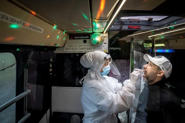 Medical staff carry out a COVID-19 PCR tests in a “Partybus” with music and disco lights converted into a mobil lab in Ishoj, Denmark, on February 23 2021 amid the novel coronavirus COVID-19 pandemic. (Photo by Mads Claus Rasmussen/Ritzau Scanpix via AFP Photo)