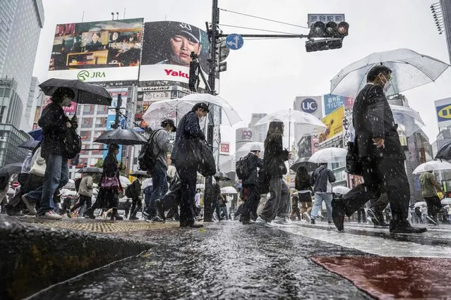 People use their umbrellas to shelter from the rain as they walk through Shibuya district in Tokyo on June 2, 2023. (Photo by Yuichi Yamazaki/AFP Photo)